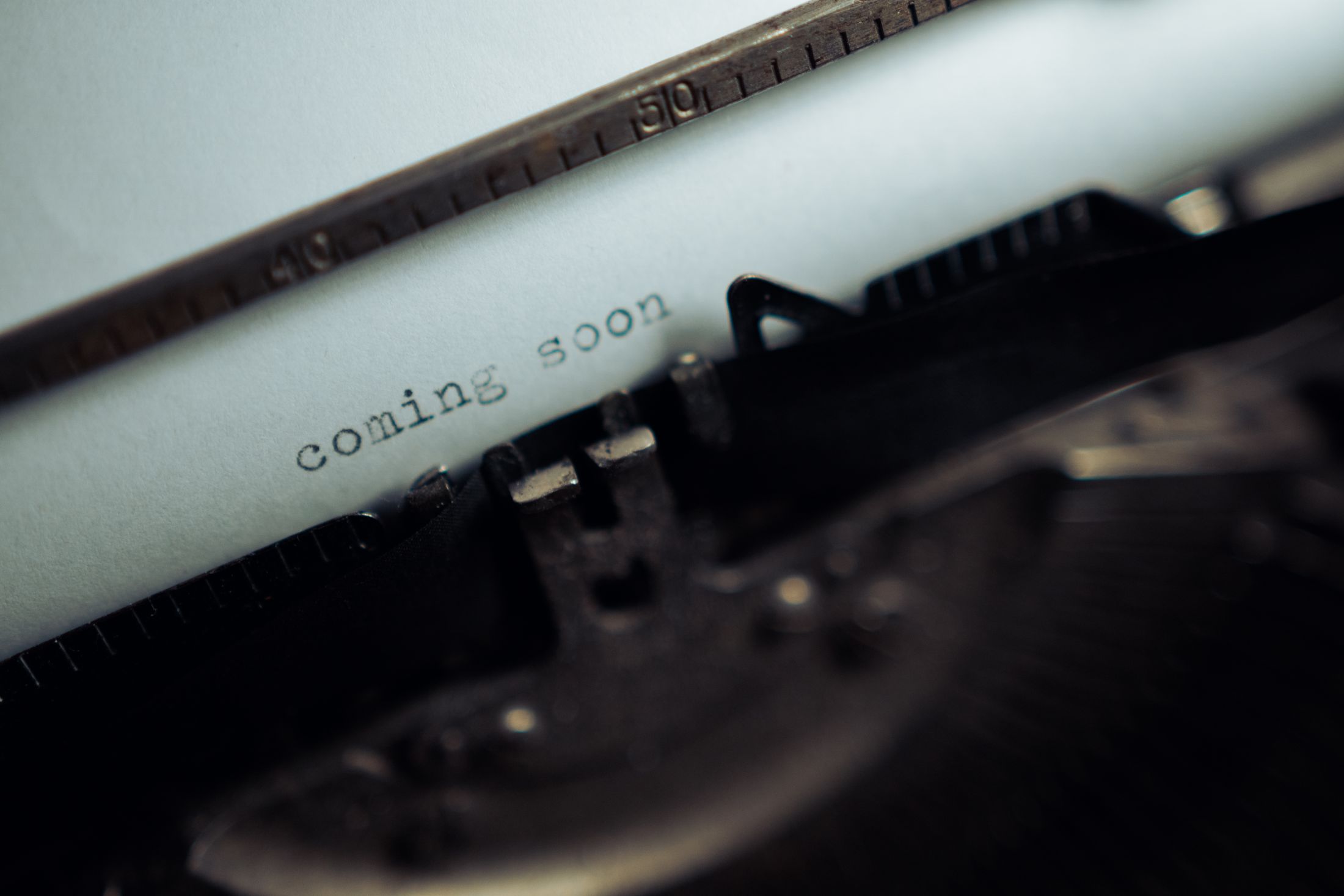 A sheet of paper in a typewriter reading &ldquo;coming soon&rdquo;